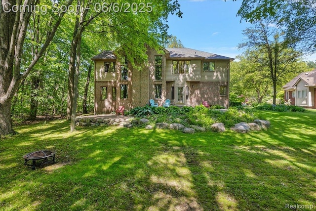 53629 Wayburn Ct, Utica, MI 48315 - back of property featuring an outdoor fire pit, a lawn, and brick siding