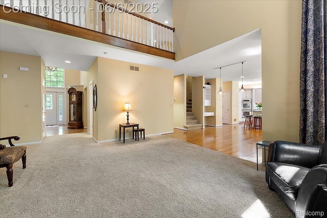 53629 Wayburn Ct, Utica, MI 48315 - living area featuring a towering ceiling, light carpet, stairway, and baseboards