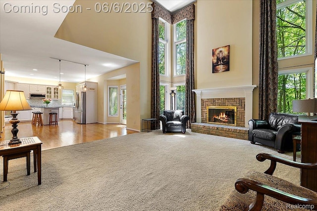 53629 Wayburn Ct, Utica, MI 48315 - living area with light colored carpet, a brick fireplace, a high ceiling, and baseboards