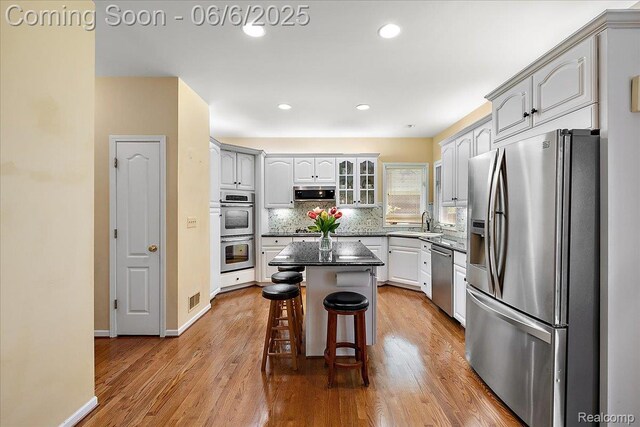 53629 Wayburn Ct, Utica, MI 48315 - kitchen featuring stainless steel appliances, a sink, a kitchen bar, wood finished floors, and tasteful backsplash