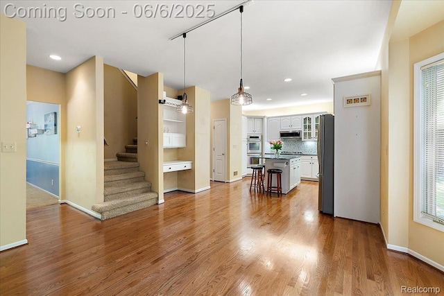 53629 Wayburn Ct, Utica, MI 48315 - kitchen with a kitchen bar, exhaust hood, appliances with stainless steel finishes, baseboards, and wood finished floors