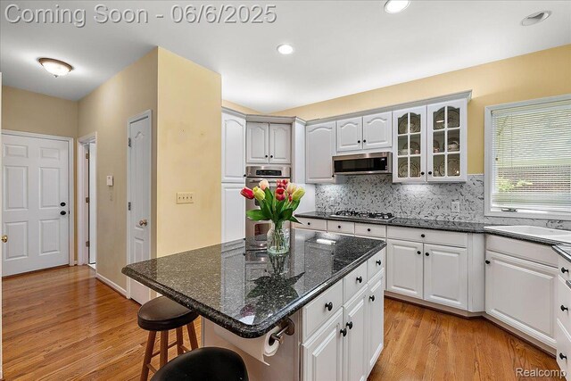 53629 Wayburn Ct, Utica, MI 48315 - kitchen featuring a kitchen breakfast bar, light wood-style flooring, stainless steel appliances, glass insert cabinets, and recessed lighting