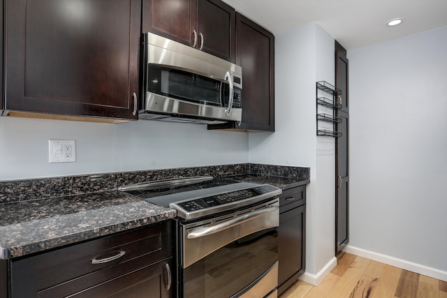 1300 E Lafayette St Unit 1604, Detroit, MI 48207 - kitchen with stainless steel appliances, light wood-style flooring, dark brown cabinets, dark stone countertops, and baseboards