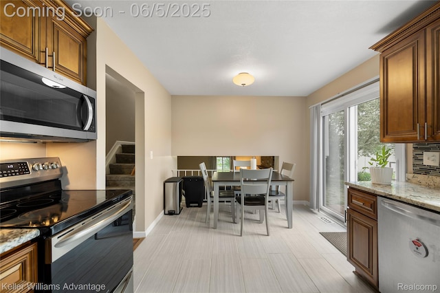 3714 Prairie Ave, Berkley, MI 48072 - kitchen featuring appliances with stainless steel finishes, baseboards, light stone countertops, and brown cabinetry