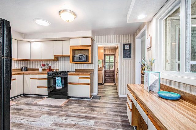 61564 Park St, Cassopolis, MI 49031 - kitchen featuring black appliances, butcher block countertops, white cabinetry, wood finished floors, and wallpapered walls