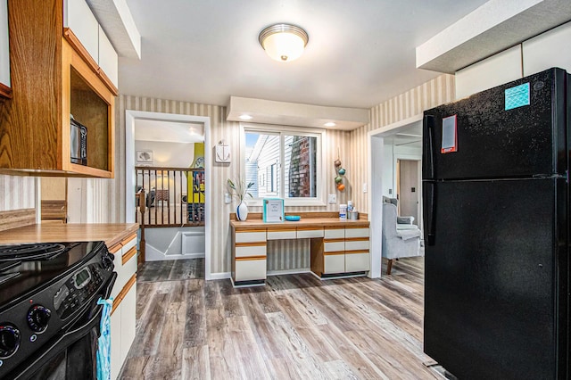 61564 Park St, Cassopolis, MI 49031 - kitchen with black appliances, wood finished floors, wallpapered walls, and light countertops
