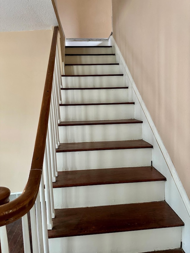 stairs featuring a textured ceiling