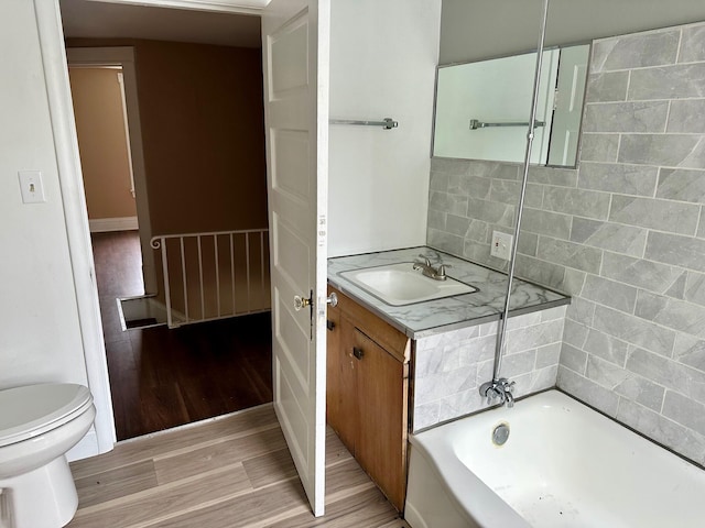 full bathroom featuring wood finished floors, toilet, a bathtub, and vanity