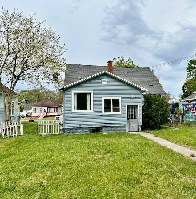 rear view of property with a chimney and roof with shingles