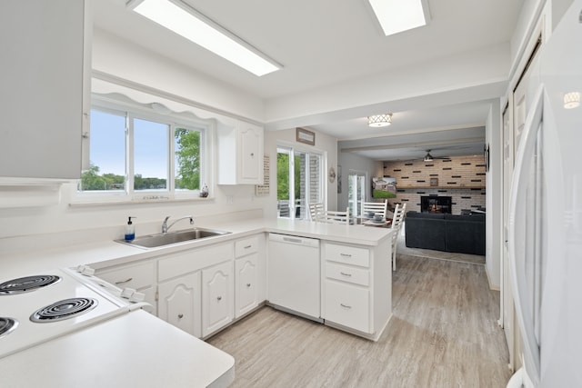 3732 Loch Dr, Highland, MI 48357 - kitchen featuring white appliances, a sink, a peninsula, a fireplace, and white cabinetry