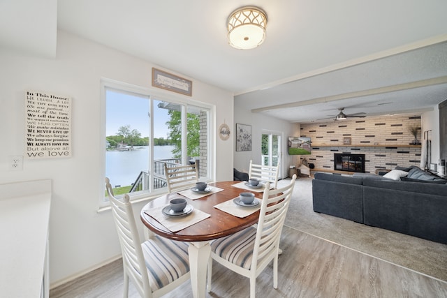 3732 Loch Dr, Highland, MI 48357 - dining area with light wood-style flooring, a large fireplace, ceiling fan, and baseboards