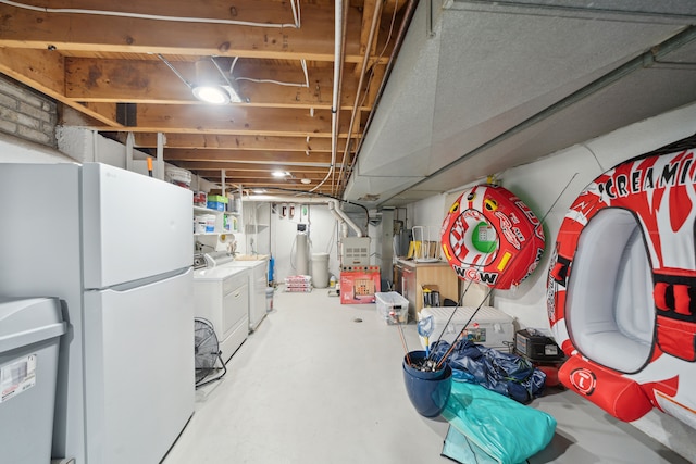 3732 Loch Dr, Highland, MI 48357 - unfinished below grade area with washing machine and clothes dryer, freestanding refrigerator, and heating unit