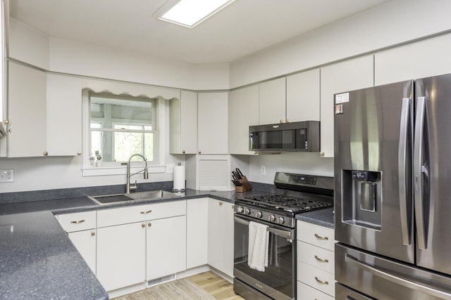 9561 Springville Hwy, Onsted, MI 49265 - kitchen featuring appliances with stainless steel finishes, a sink, white cabinets, and light wood-style floors