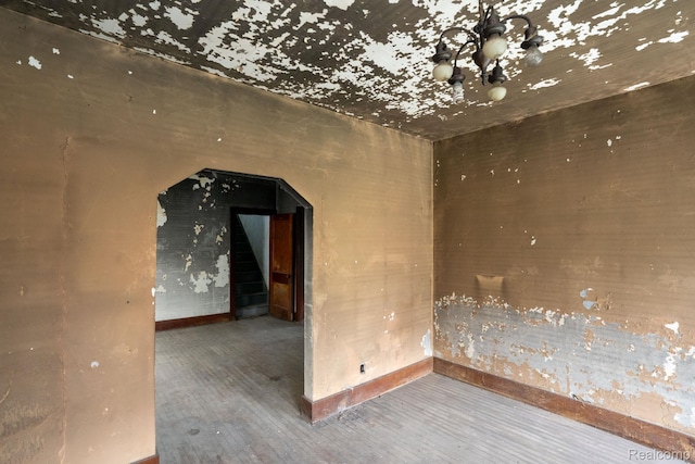 17257 Moenart St, Hamtramck, MI 48212 - empty room featuring arched walkways, wood finished floors, a chandelier, and baseboards