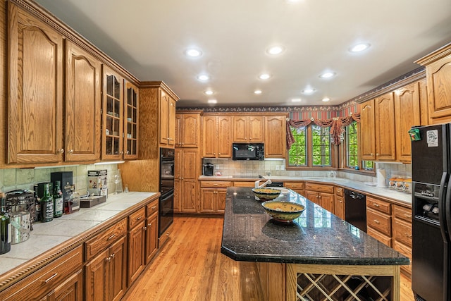 1506 Golfside Ct, Flushing, MI 48433 - kitchen with black appliances, glass insert cabinets, tasteful backsplash, light wood-style flooring, and a center island