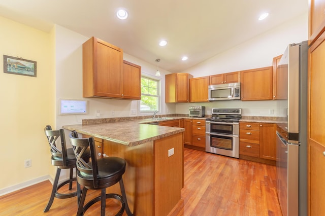 1373 Kristen Path, Saint Joseph, MI 49085 - kitchen with stainless steel appliances, a peninsula, a sink, light wood-style floors, and a kitchen bar