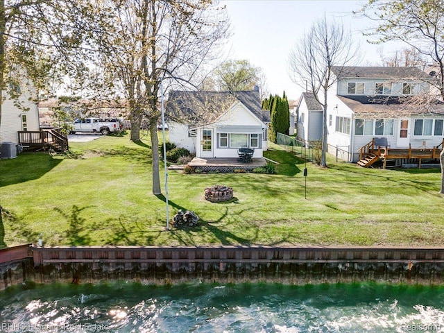 5222 S Channel Dr, Harsens Island, MI 48028 - rear view of property featuring a fire pit, a deck with water view, and a lawn