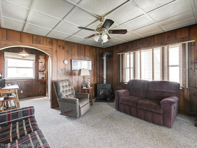 5222 S Channel Dr, Harsens Island, MI 48028 - carpeted living room featuring wood walls, a wood stove, ceiling fan, and arched walkways