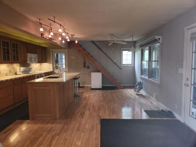 9332 W 10 Mile Rd, Irons, MI 49644 - kitchen with a sink, white microwave, a kitchen island with sink, wood finished floors, and glass insert cabinets