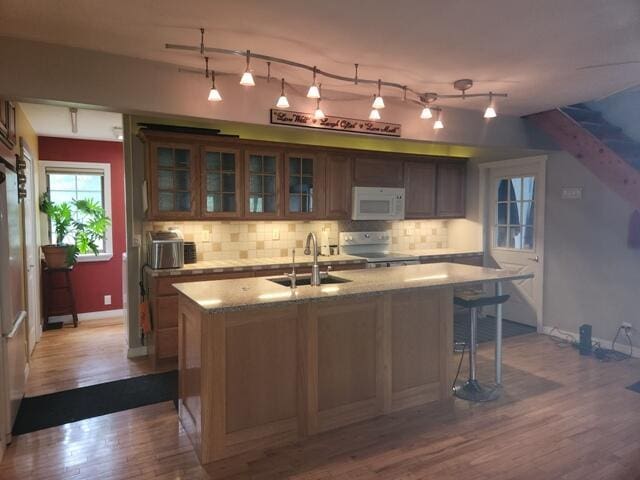 9332 W 10 Mile Rd, Irons, MI 49644 - kitchen with stainless steel electric range oven, a sink, white microwave, wood finished floors, and decorative backsplash