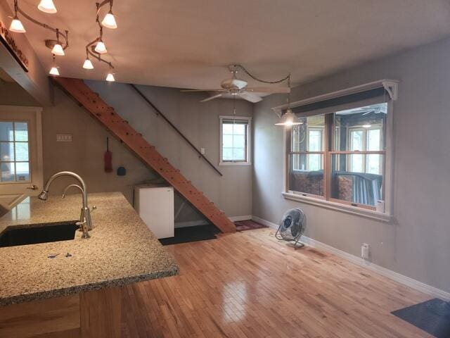 9332 W 10 Mile Rd, Irons, MI 49644 - kitchen featuring a sink, ceiling fan, baseboards, wood finished floors, and light stone counters