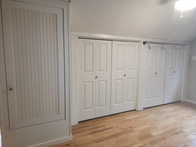 9332 W 10 Mile Rd, Irons, MI 49644 - unfurnished bedroom featuring light wood-style flooring, baseboards, lofted ceiling, and a ceiling fan
