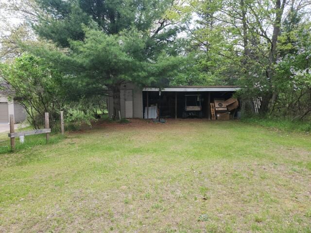 9332 W 10 Mile Rd, Irons, MI 49644 - view of grassy yard featuring a carport, an outbuilding, and an outdoor structure