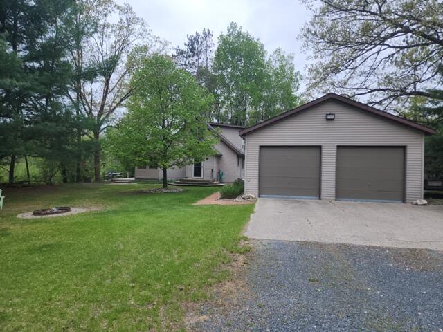 9332 W 10 Mile Rd, Irons, MI 49644 - view of front of house with an outdoor fire pit and a front lawn