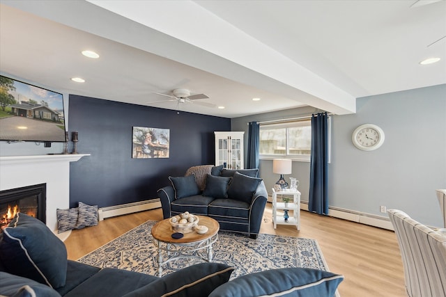 3761 Hunt Rd, Lapeer, MI 48446 - living room with a baseboard heating unit, a glass covered fireplace, wood finished floors, a ceiling fan, and baseboard heating