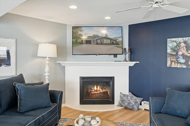3761 Hunt Rd, Lapeer, MI 48446 - living area featuring a glass covered fireplace, wood finished floors, recessed lighting, a ceiling fan, and baseboard heating