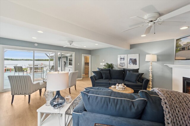 3761 Hunt Rd, Lapeer, MI 48446 - living area featuring ceiling fan, light wood-style flooring, a water view, recessed lighting, and a warm lit fireplace