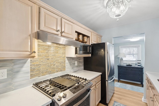 3761 Hunt Rd, Lapeer, MI 48446 - kitchen featuring stainless steel appliances, under cabinet range hood, light wood finished floors, a chandelier, and tasteful backsplash