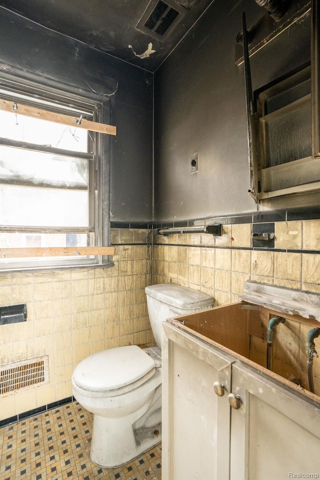 19610 Norwood St, Detroit, MI 48234 - bathroom featuring tile walls, toilet, vanity, and wainscoting