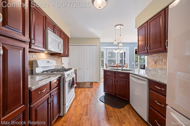 9863 Marshall Rd, South Lyon, MI 48178 - kitchen featuring white appliances, light wood finished floors, backsplash, dark brown cabinets, and a peninsula