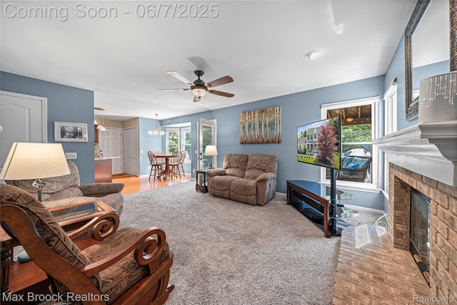 9863 Marshall Rd, South Lyon, MI 48178 - living room featuring ceiling fan, a fireplace, baseboards, a chandelier, and light carpet