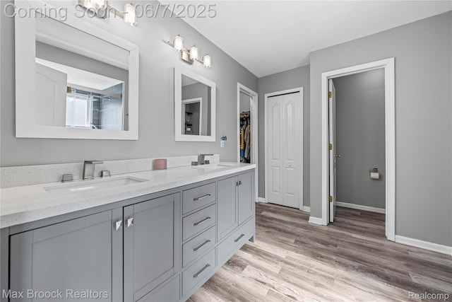 9863 Marshall Rd, South Lyon, MI 48178 - bathroom with double vanity, wood finished floors, baseboards, and a walk in closet