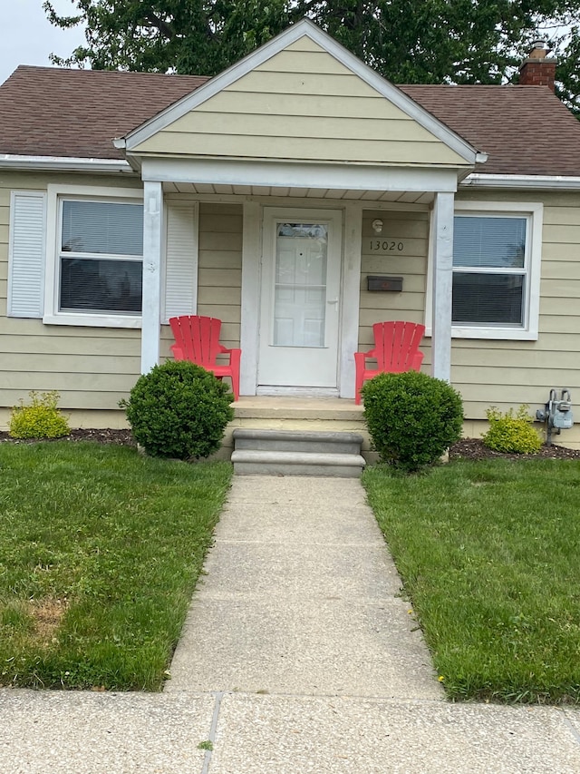 13020 Castle St, Southgate, MI 48195 - view of front of property featuring a shingled roof, a chimney, a front yard, and covered porch