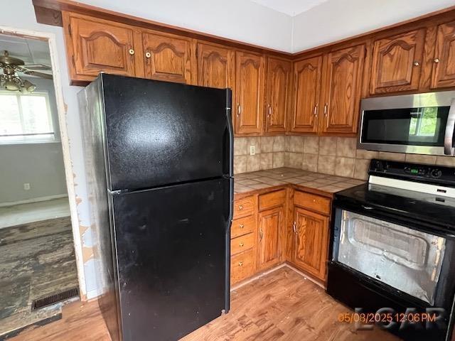 6730 Summerfield Rd, Temperance, MI 48182 - kitchen with black appliances, tile counters, brown cabinets, and light wood-type flooring