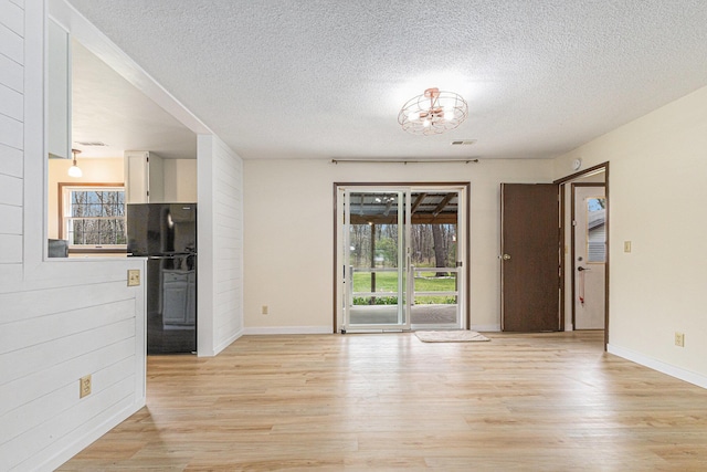 7719 Guenthardt Rd, Manistee, MI 49660 - spare room with light wood-style flooring, a textured ceiling, baseboards, and a chandelier
