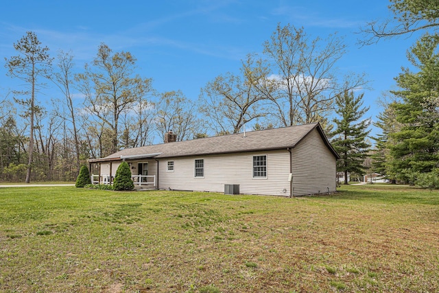 7719 Guenthardt Rd, Manistee, MI 49660 - back of property featuring a chimney, a lawn, central AC unit, and a porch