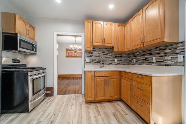 50 Elm St, River Rouge, MI 48218 - kitchen with stainless steel appliances, a sink, light wood-type flooring, light countertops, and tasteful backsplash