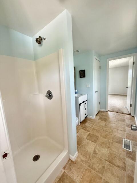 bathroom featuring a stall shower, vanity, and baseboards