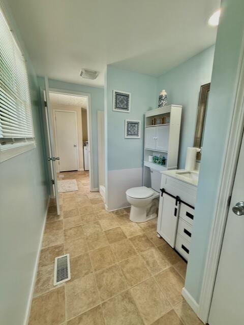 full bathroom with toilet, vanity, and baseboards