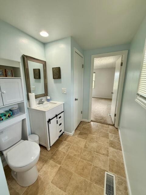 bathroom with toilet, vanity, and baseboards
