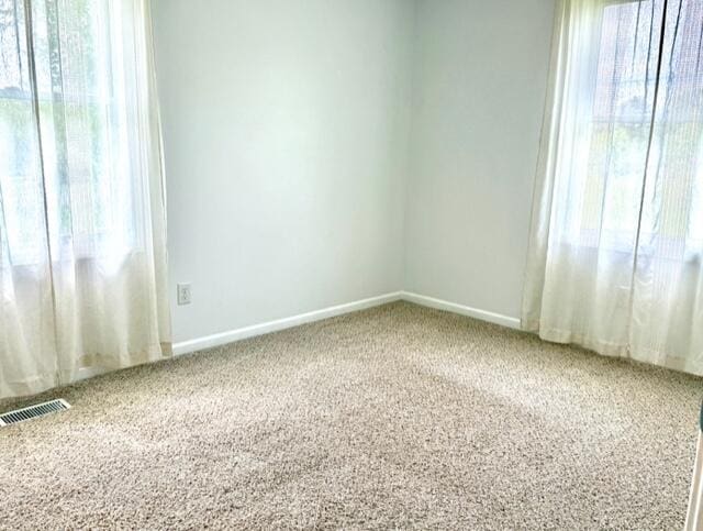 spare room featuring carpet floors and baseboards