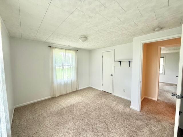 unfurnished bedroom with carpet, multiple windows, and baseboards