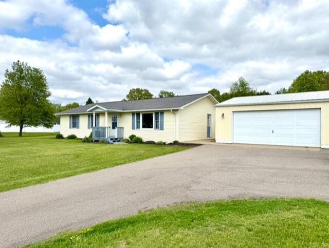 ranch-style home with a detached garage, a front yard, central AC unit, and an outbuilding