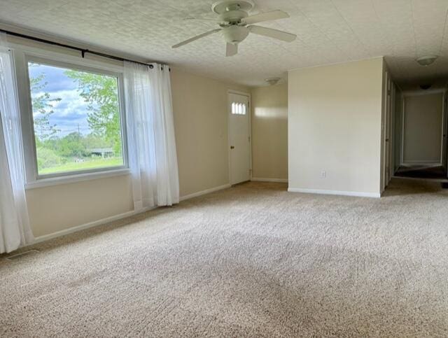 empty room with ceiling fan, carpet floors, and baseboards