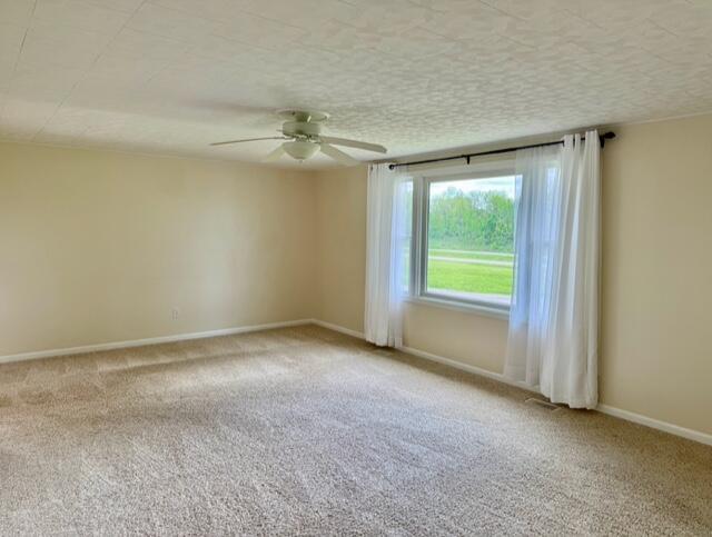 empty room with carpet floors, a ceiling fan, baseboards, and a textured ceiling