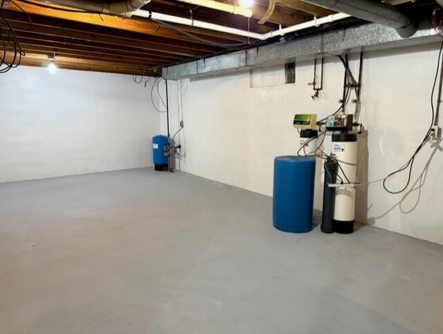 unfinished below grade area with a water pressure tank and a water softener system